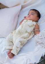 Load image into Gallery viewer, A kid wearing an cotton jumpsuit eco-printed with silver oak leaves on it sleeping on a bed with some pillows aside.