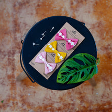 Load image into Gallery viewer, Three hair accessories combo tied on a brown card placed on a black plate with a leaf on the side for decoration.