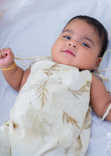 Load image into Gallery viewer, A kid wearing an cotton jumpsuit eco-printed with silver oak leaves on it sleeping on a bed.