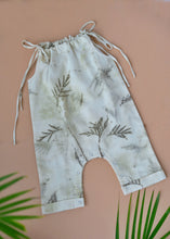 Load image into Gallery viewer, A beautiful unisex jumpsuit with wild silver oak design on it which is kept upon a pink background with some leaves aside.