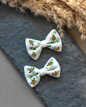 Load image into Gallery viewer, A pair of beautiful honeybee hair accessories kept on gray cloth with brown feathers aside.