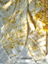 Load image into Gallery viewer, A beautiful muslin baby swaddle with marigold ecoprinted on it with some flowers aside.