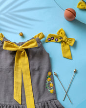 Load image into Gallery viewer, A beautiful dress with extra-long bow tie strap with a matching hair accessory kept on a blue floor with some leaf, flower and needle aside.