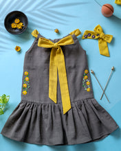 Load image into Gallery viewer, A beautiful dress with extra-long bow tie strap with a matching hair accessory kept on a blue floor with some leaf, flower and needle aside.