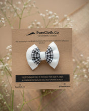 Load image into Gallery viewer, A mini black and white hair accessory tied on a brown card with some flowers in the background.
