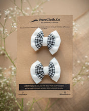Load image into Gallery viewer, A pair of mini black and white hair accessory tied on a brown card with some flowers in the background.