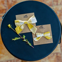 Load image into Gallery viewer, An organic cotton handmade bow hair accessories for kids tied upon a brown card Placed upon a dark blue plate with some leaves aside.