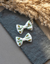 Load image into Gallery viewer, A pair of beautiful honeybee hair accessories kept on gray cloth with brown feathers aside.