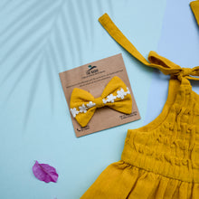 Load image into Gallery viewer, A beautiful adjustable shoulder strap dress with matching hair accessory kept upon a blue background with some leaf petals aside.