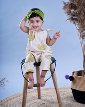 Load image into Gallery viewer, A baby girl wearing a jumpsuit with matching hair accessories sitting on a chair with some artificial plant aside.
