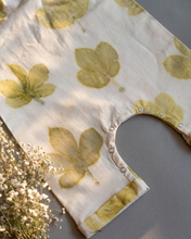 Load image into Gallery viewer, A cute baby girl dress made of eco-printed Indian maple leaves on it along with some flower aside.