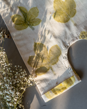 Load image into Gallery viewer, A cute baby girl dress made of eco-printed Indian maple leaves on it along with some flower aside.