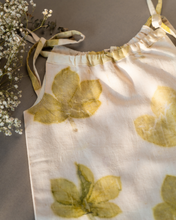 Load image into Gallery viewer, A cute baby girl dress made of eco-printed Indian maple leaves on it along with some flower aside.