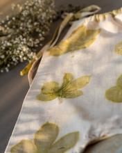 Load image into Gallery viewer, A cute baby girl dress made of eco-printed Indian maple leaves on it along with some flower aside.