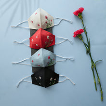 Load image into Gallery viewer, A different color organic cotton hand-embroidered adjustable face masks kept upon a grey sheet with some flowers aside.