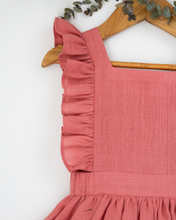 Load image into Gallery viewer, A beautiful dress with a criss-cross back hung on a hanger with a stem of leaves upon it.