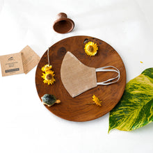 Load image into Gallery viewer, A beautiful, patterned face mask kept upon a round wooden log with some flower, leaf, toys and cards aside.