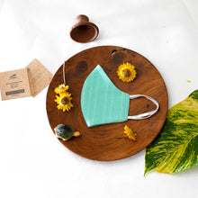 Load image into Gallery viewer, A beautiful, patterned face mask kept upon a round wooden log with some flower, leaf, toys and cards aside.