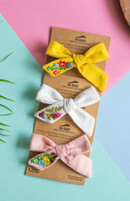 Load image into Gallery viewer, A beautiful combo of hand embroidery hair clips attached to the brown card is kept upon a pastel color background with leave and a round wooden log aside.