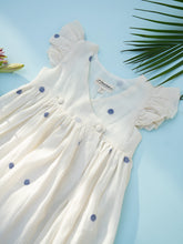 Load image into Gallery viewer, A zoomed in view of a handwoven cotton wrap dress with black dotted design, a baby girl&#39;s dress on a light bluish background.
