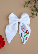 Load image into Gallery viewer, A Red Embroidered White Hairclip for kids hair accessories placed on a light brown background with flowers and leaves as decor
