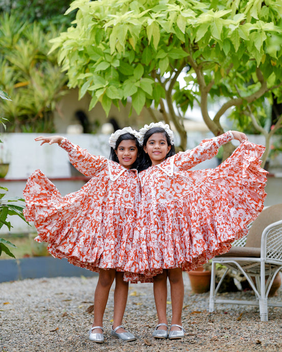 Beautiful and bold prints, voluminous layers, and frill-edged collar dress with a toy and leaf aside.