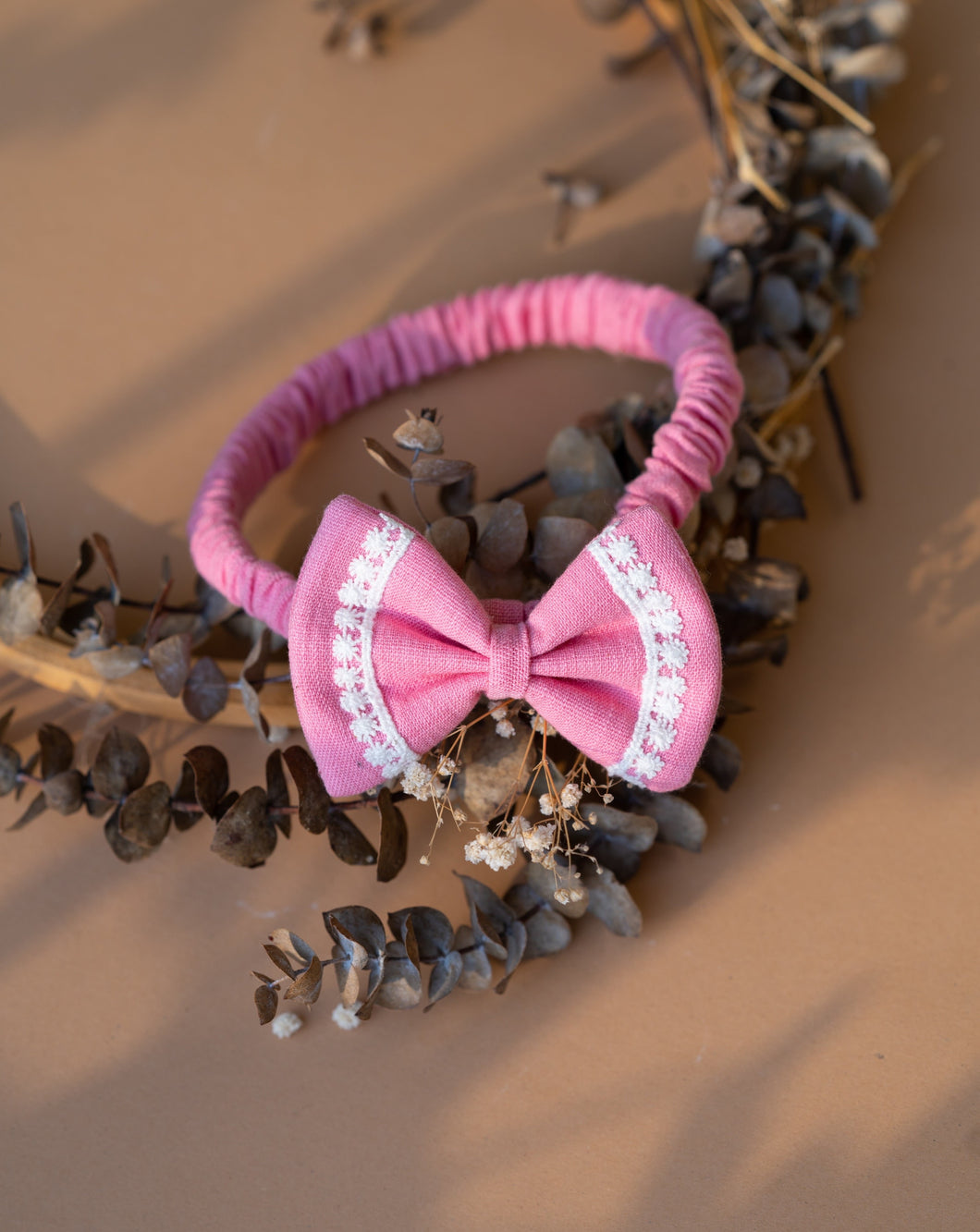 Beautiful hair accessories of headband with bow clip kept upon a dried leaf.