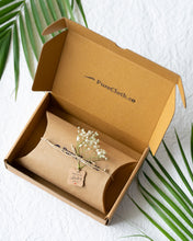 Load image into Gallery viewer, A brown gift box with wrapped gift box knotted with thread along with a flower with white background with some leaves aside it.
