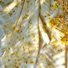 Load image into Gallery viewer, A beautiful muslin baby swaddle with marigold ecoprinted on it with some flowers aside.
