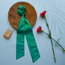 Load image into Gallery viewer, A beautiful silk hair scrunchie kept upon a round wooden log with some flowers and brown card aside.
