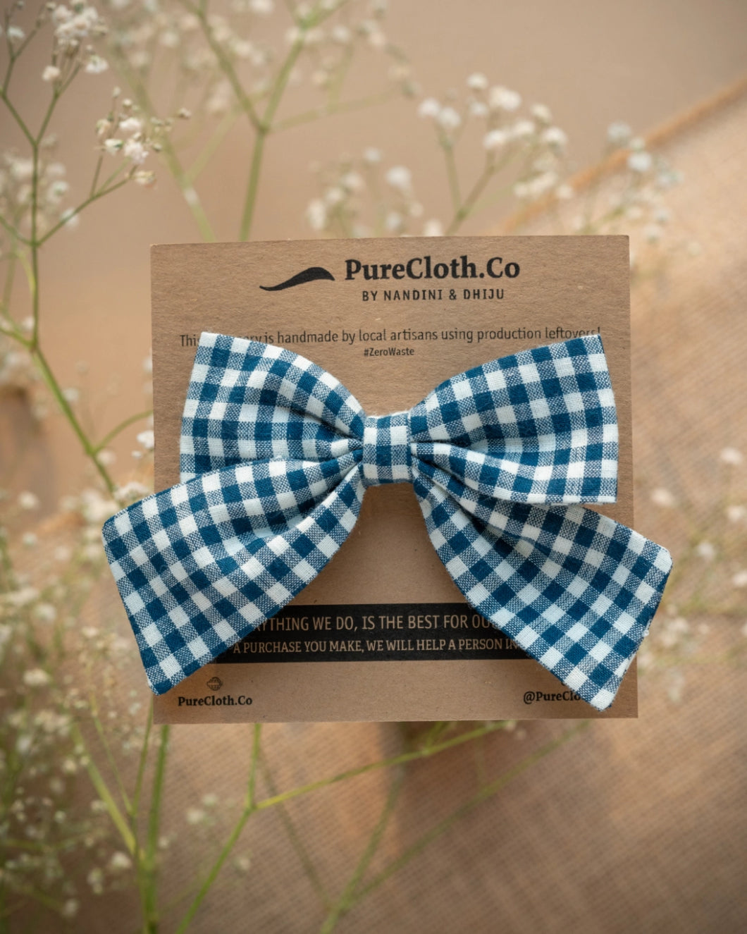 An organic cotton handmade bow hair accessory for kidswear tied upon a brown card.