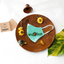 Load image into Gallery viewer, A beautiful organic embroidery face mask kept on a wooden plate with tortoise, flowers, cards and leaf aside.
