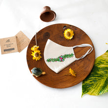 Load image into Gallery viewer, A beautiful organic embroidery face mask kept on a wooden plate with tortoise, flowers, cards and leaf aside.

