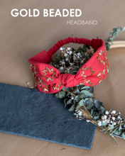 Load image into Gallery viewer, A beautiful gold-beads hand crafted on red cotton fabric hair accessories kept on a dried leaf tiara with some gray sheet under it.
