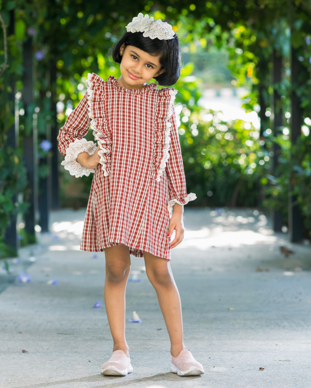 A girl wearing beautiful lace shift dress with matching accessory posing in the middle of the road.