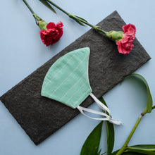 Load image into Gallery viewer, An adjustable mask kept on a grey sheet with some flowers aside.
