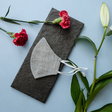 Load image into Gallery viewer, An adjustable mask kept on a grey sheet with some flowers aside.
