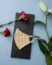 Load image into Gallery viewer, A stripped adjustable mask kept on a grey sheet with some flowers aside.
