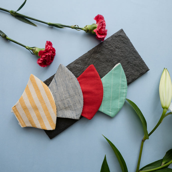 A stripped adjustable mask kept on a grey sheet with some flowers aside.