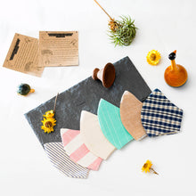 Load image into Gallery viewer, A different color and multi-patterned face masks kept upon a grey sheet with some flower, toys and cards aside.
