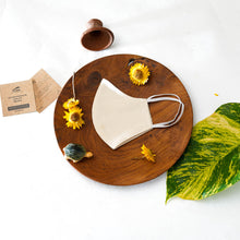 Load image into Gallery viewer, A beautiful, patterned face mask kept upon a round wooden log with some flower, leaf, toys and cards aside.
